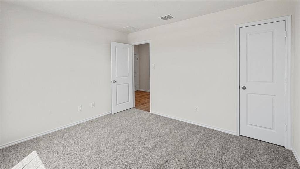 215 Yates Street, Bullard, TX 75757 Neutral wall color, grey carpet, white trim, white panel doors, and wood-finish flooring visible through doorway