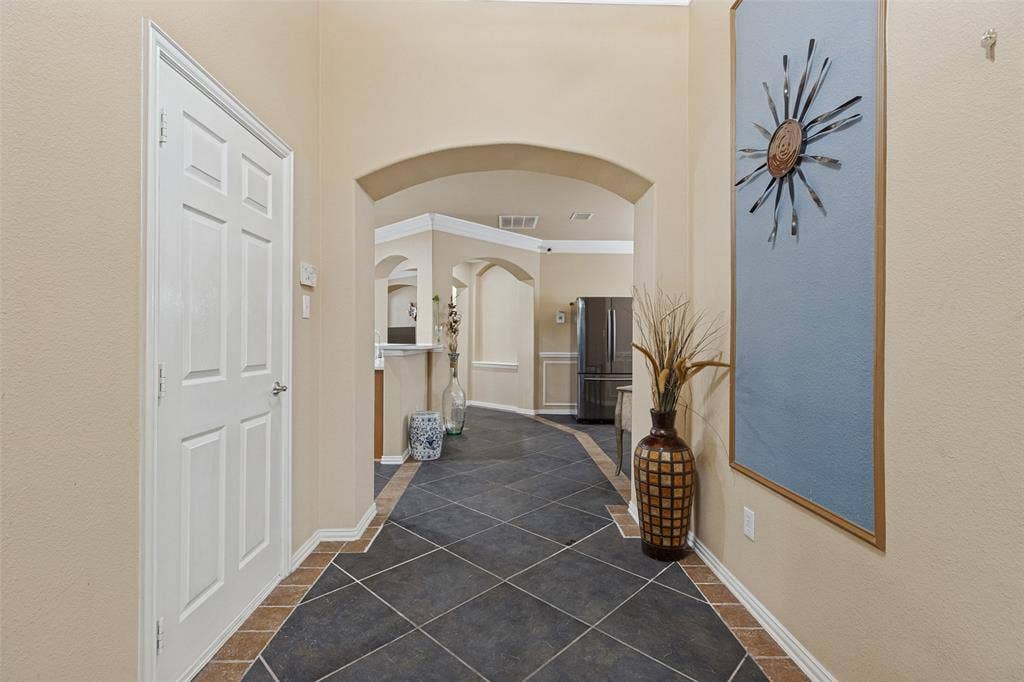 Arched doorways, dark tile flooring with a light tile border, and neutral wall tones