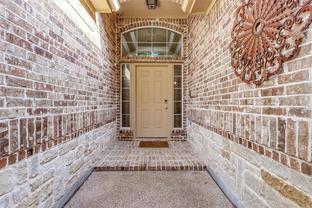 Brick and stone exterior with arched transom window, side light window, and brick flooring