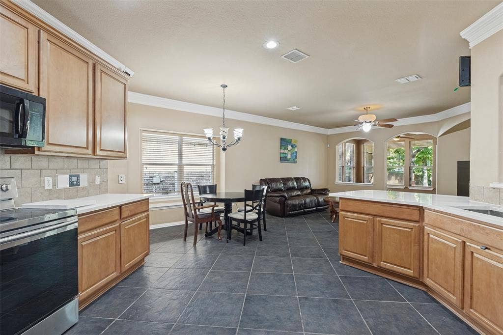 Kitchen with wood cabinetry, light countertops, and dark tile flooring