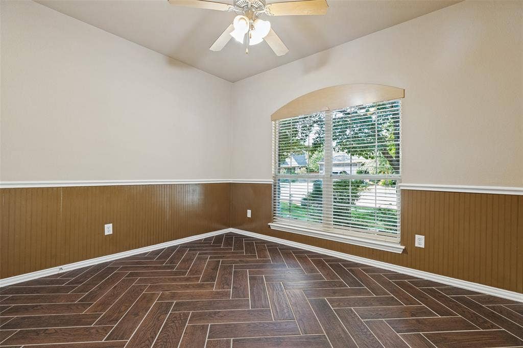Wood look ceramic tile in a herringbone pattern, beadboard wainscoting, and a large window.