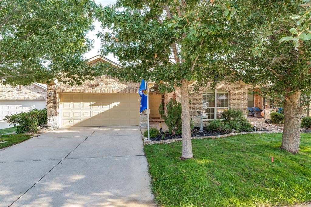 Brick exterior with an attached two-car garage, and established landscaping with mature trees