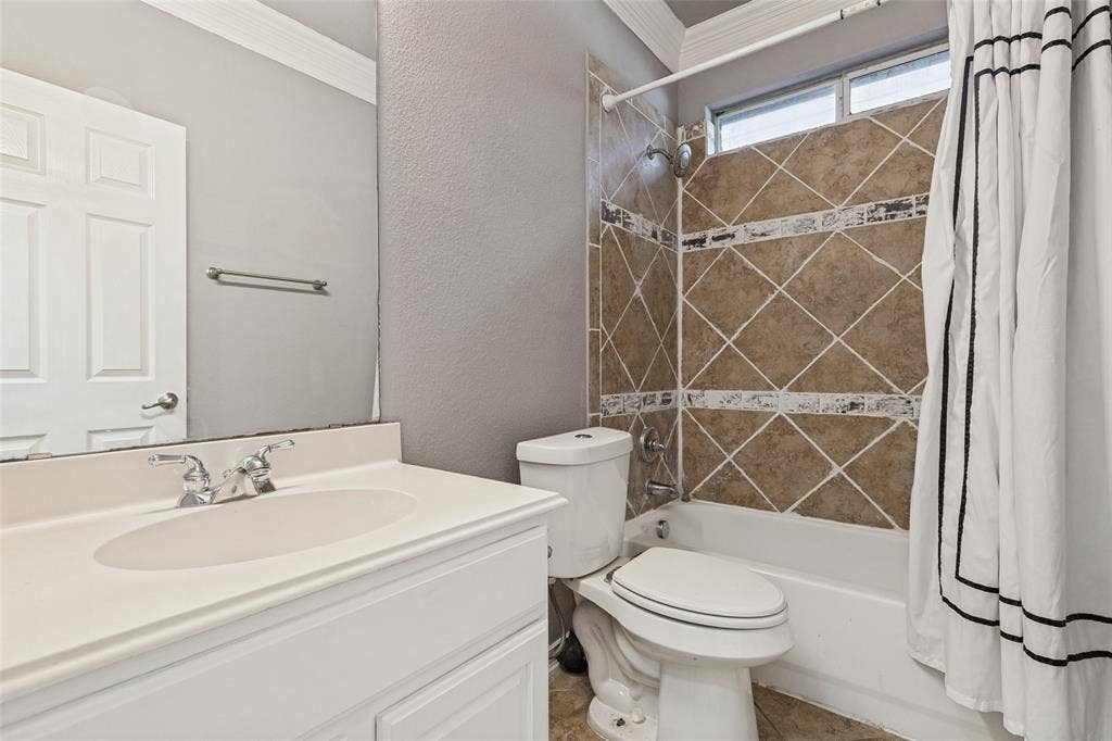 Bathroom featuring a white vanity, tiled shower surround with accent bands, and an upper window