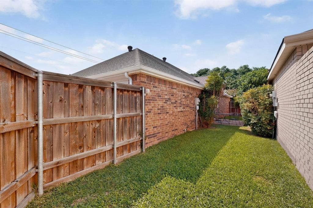 2702 Garden Springs Drive, Richardson, TX 75082 Fenced backyard featuring a wood fence, brick exterior, and a manicured lawn