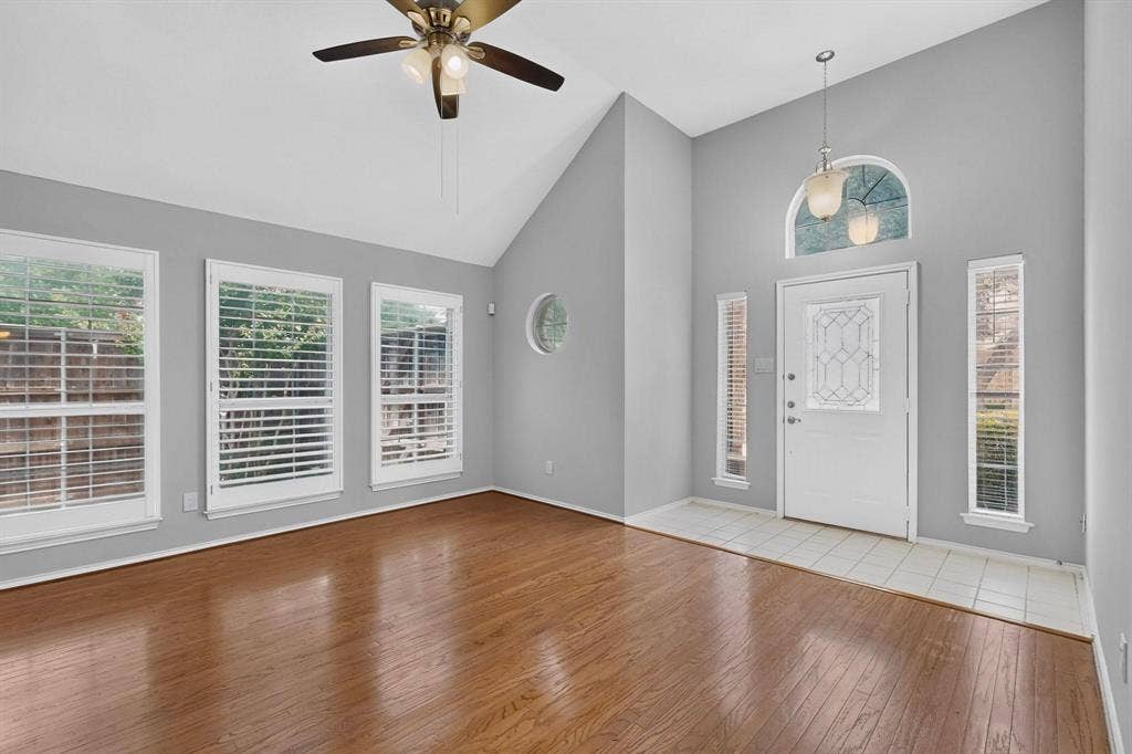 2702 Garden Springs Drive, Richardson, TX 75082 Vaulted ceiling with a ceiling fan, wood-finish flooring, multiple windows with plantation shutters, white entry door with decorative glass, and a tiled entry area