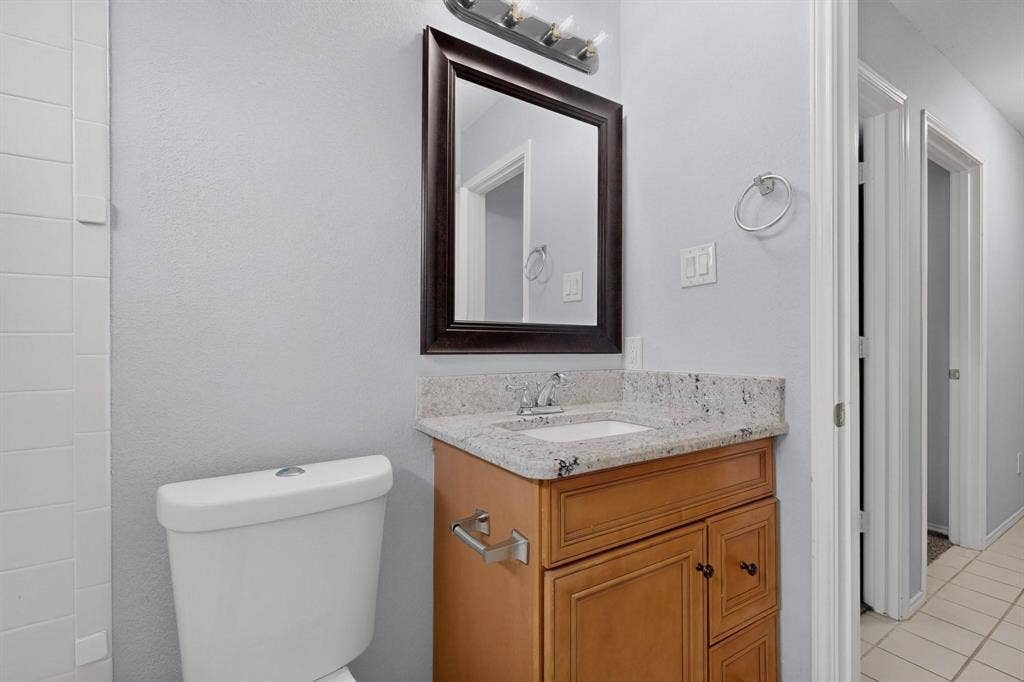 2702 Garden Springs Drive, Richardson, TX 75082 Vanity with light wood-finish cabinetry, integrated sink, and stone-finish countertop
