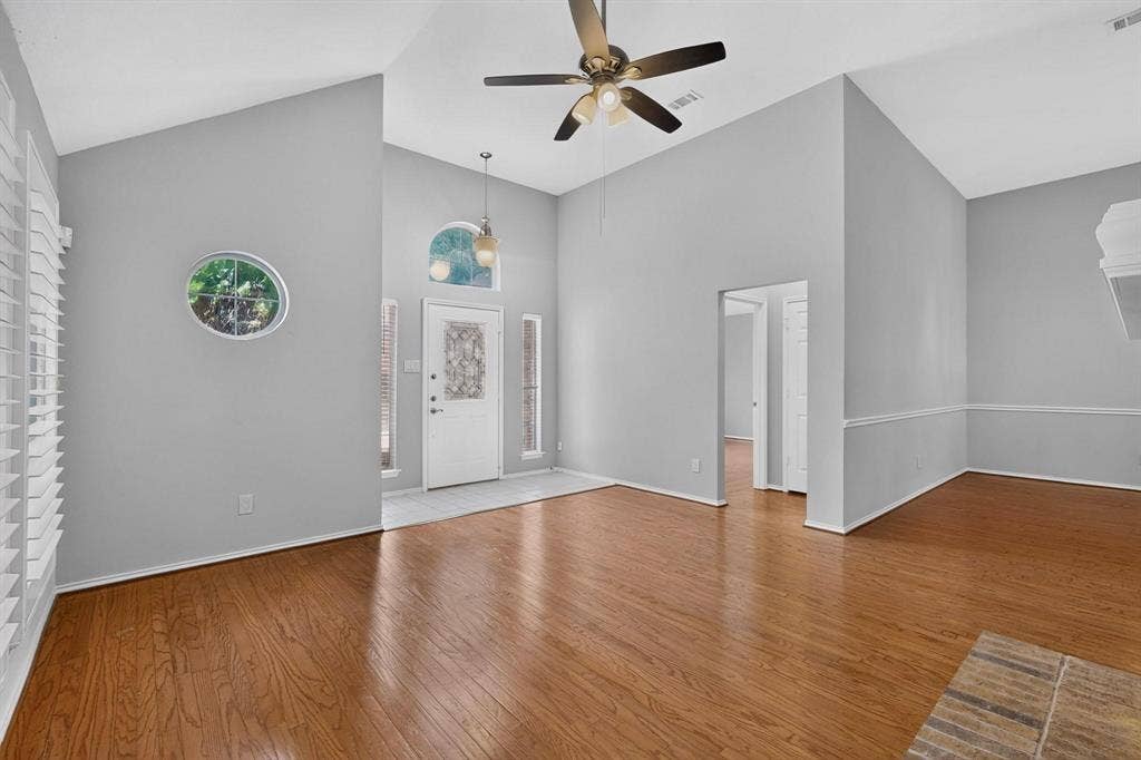 2702 Garden Springs Drive, Richardson, TX 75082 Vaulted ceilings, wood-finish flooring, decorative oval window, arched transom window, and a ceiling fan with integrated lighting