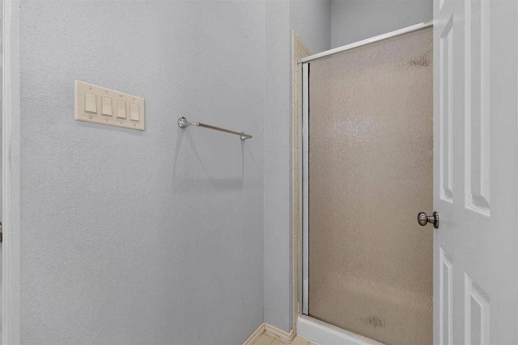 2702 Garden Springs Drive, Richardson, TX 75082 Enclosed shower with frosted glass door, light gray walls, and white trim