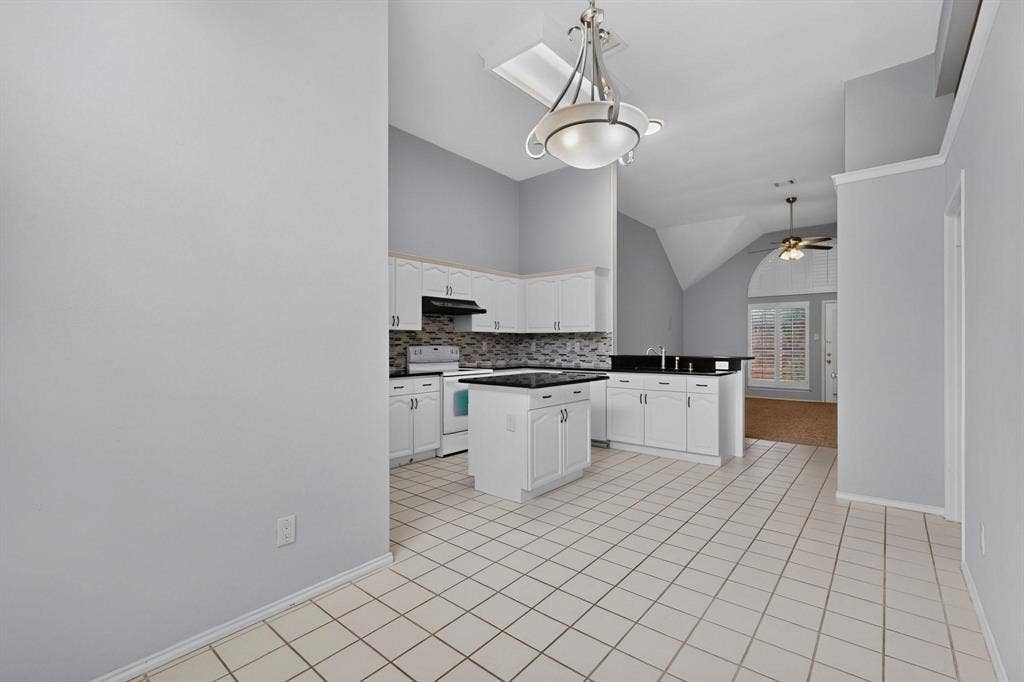 2702 Garden Springs Drive, Richardson, TX 75082 Kitchen featuring white cabinetry, dark countertops, a mosaic tile backsplash, a center island, and tile flooring