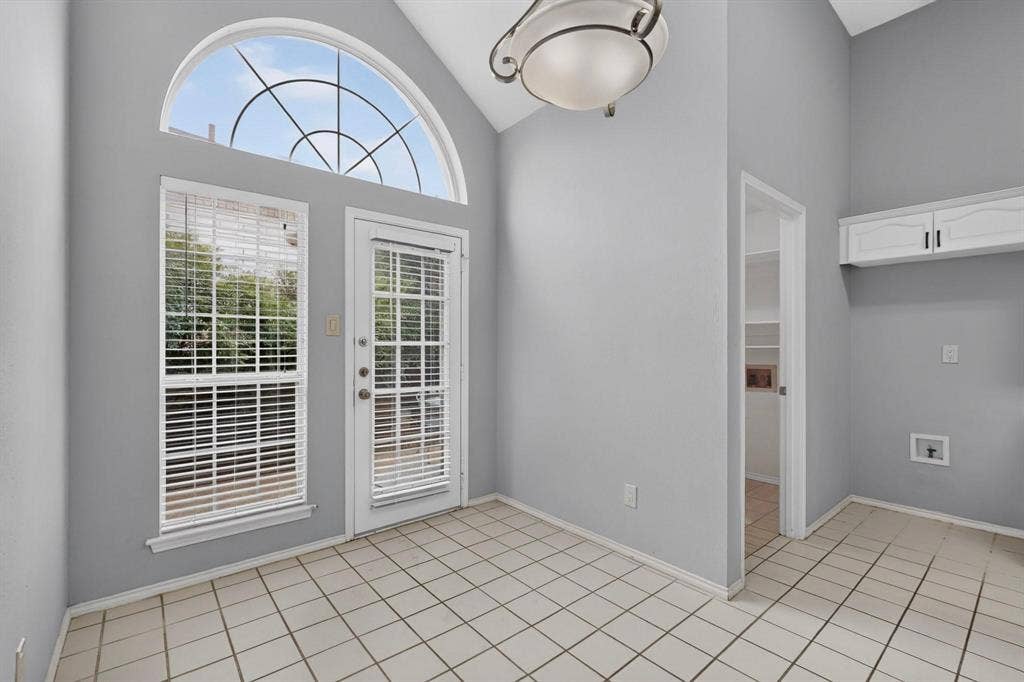 2702 Garden Springs Drive, Richardson, TX 75082 Ceramic tile flooring, white shaker-style wall cabinets, arched transom window, glass-panel exterior door, and recessed shelving