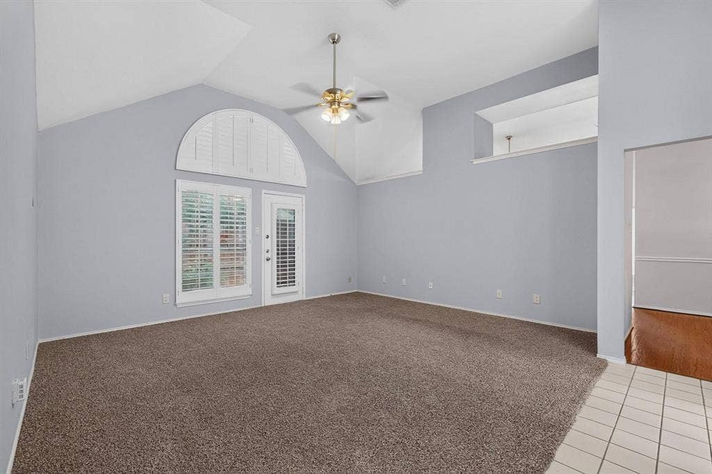 2702 Garden Springs Drive, Richardson, TX 75082 Vaulted ceiling with an illuminated ceiling fan, a window with plantation shutters, a glass-paneled door, and a tiled entry