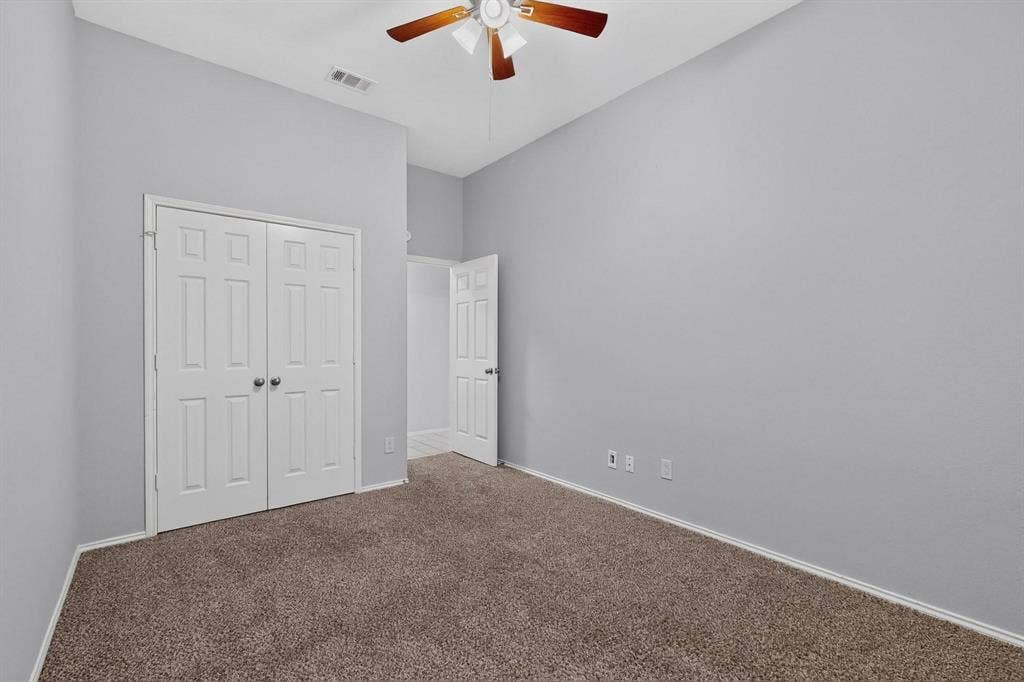 2702 Garden Springs Drive, Richardson, TX 75082 Neutral gray wall finish, brown carpet, bi-fold closet doors, paddle ceiling fan, and white trim