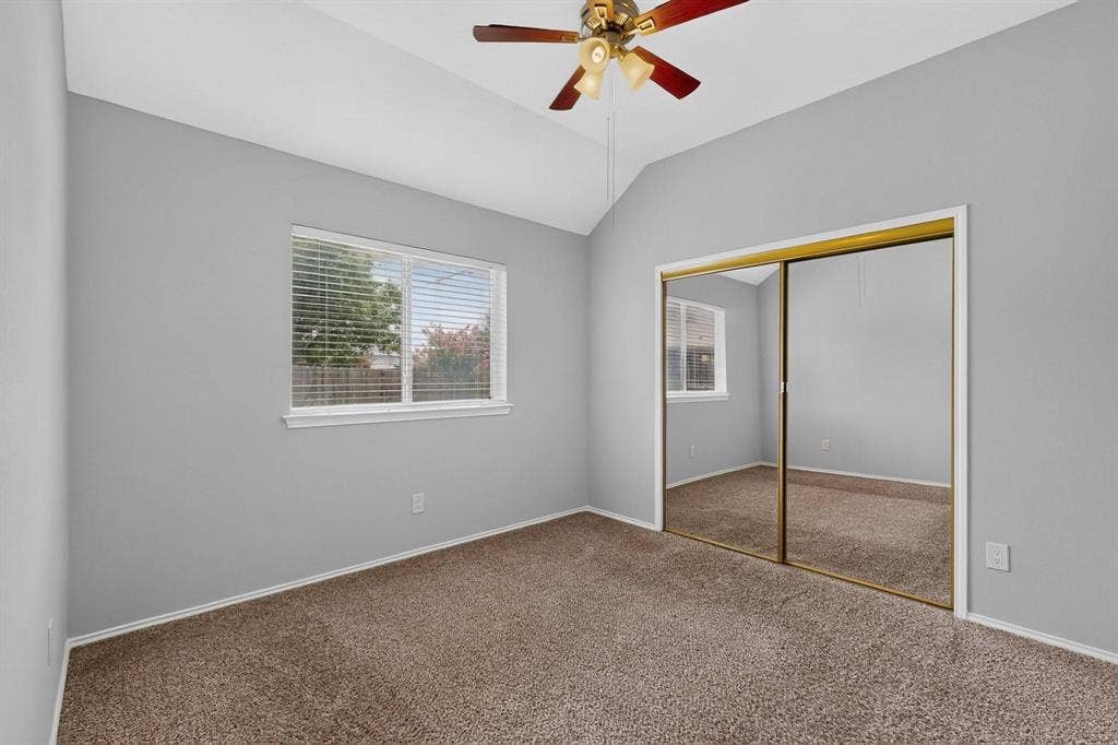 2702 Garden Springs Drive, Richardson, TX 75082 Vaulted ceiling with a ceiling fan, window with blinds, mirrored closet doors, and carpeted flooring
