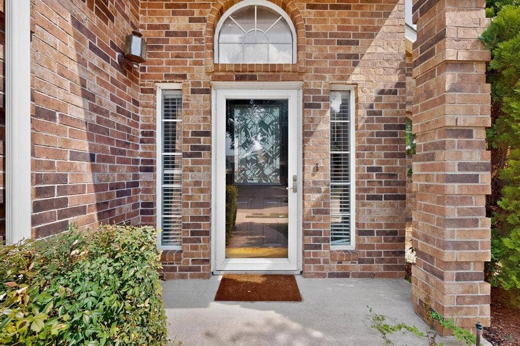 2702 Garden Springs Drive, Richardson, TX 75082 Brick exterior with a prominent arched window above the entry door, flanked by two vertical windows