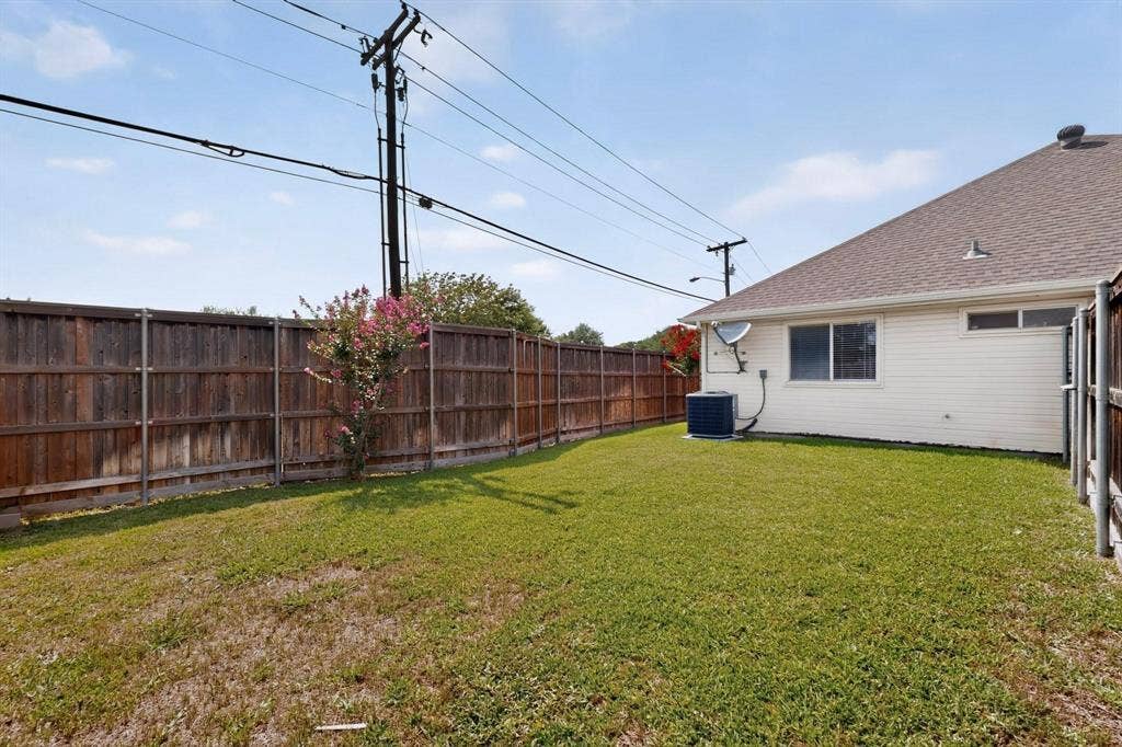 2702 Garden Springs Drive, Richardson, TX 75082 Expansive backyard with a manicured lawn, full wood privacy fence, and a blooming shrub