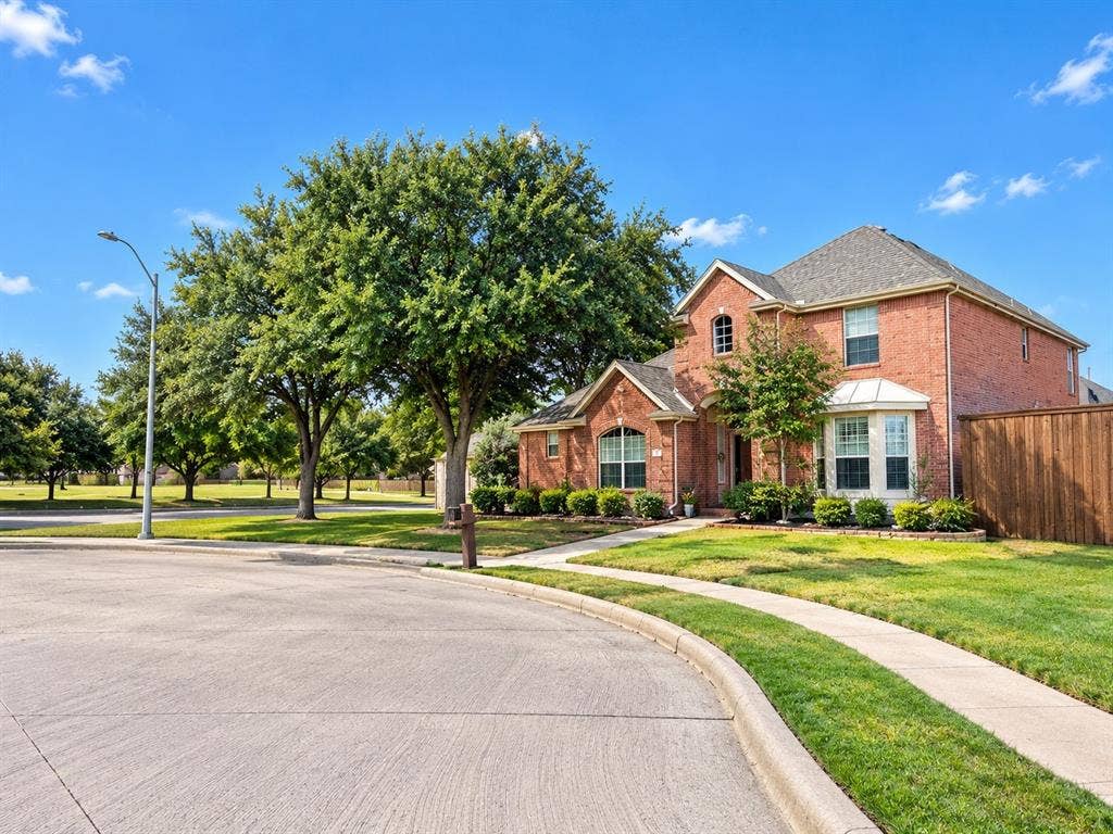 10316 Donley Drive, Irving, TX 75063 Brick exterior construction, prominent bay window, established landscaping, concrete sidewalks, and a wooden privacy fence