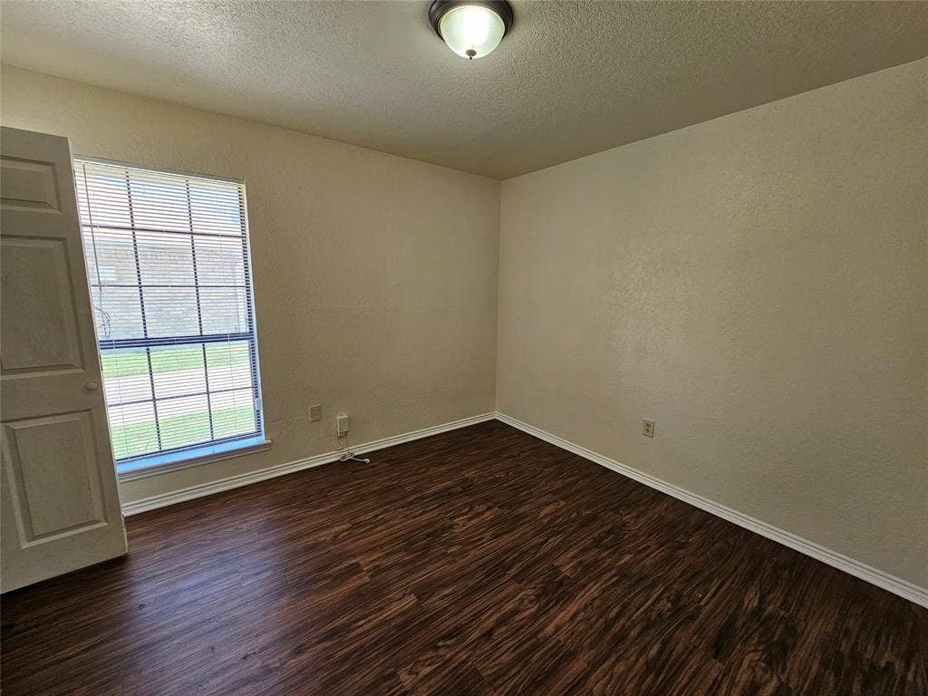 Neutral wall tones, wood-finish flooring, white trim, and a window with blinds