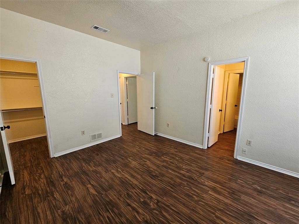 Wood-finish flooring, white baseboards, and built-in closet shelving