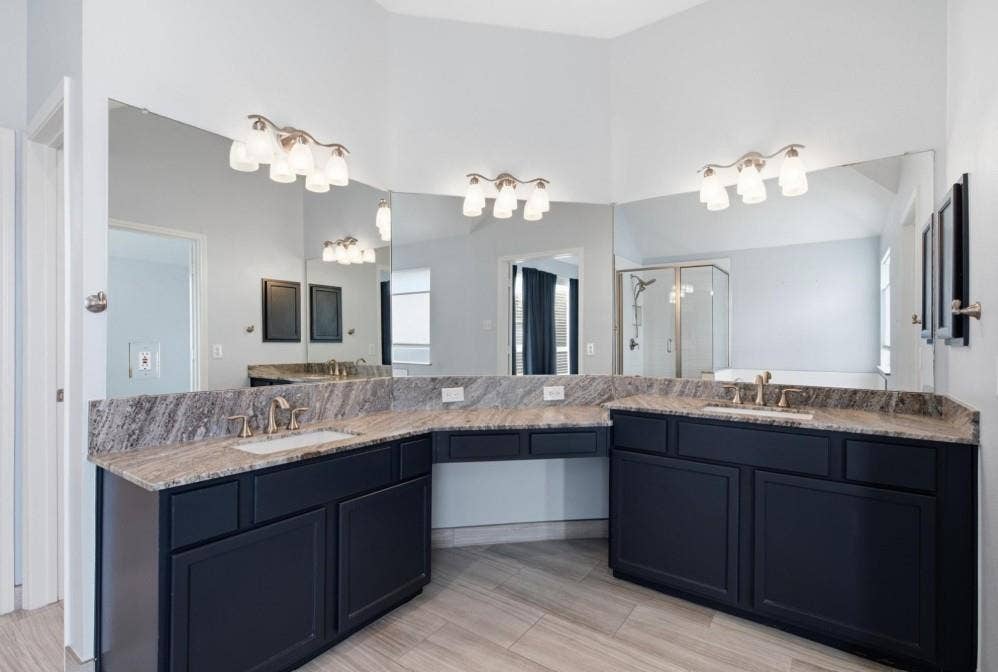 Dual vanities with stone countertops, undermount sinks, and dark cabinetry