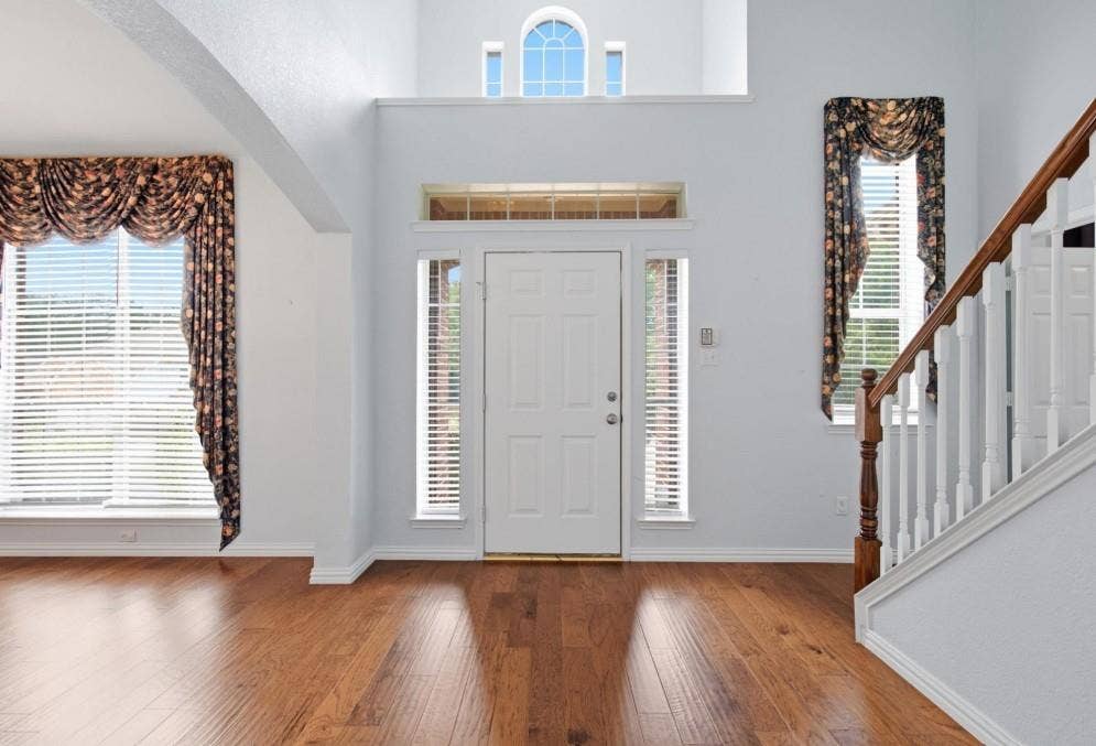 Two-story entry with wood-finish flooring, a prominent staircase, and an arched window