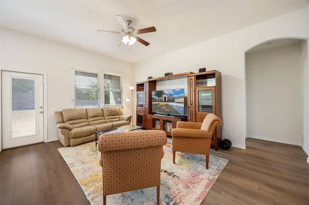 1101 Crepe Myrtle Lane, Anna, TX 75409 Vaulted ceiling with a ceiling fan, wood-finish flooring, two windows with blinds, glass-paneled exterior door, and an arched entryway