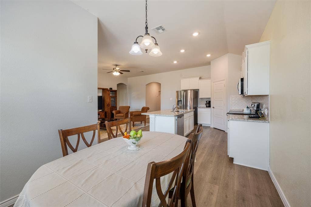 1101 Crepe Myrtle Lane, Anna, TX 75409 Open-concept living space featuring wood-finish flooring, recessed lighting, white cabinetry, and a kitchen island with stone countertops