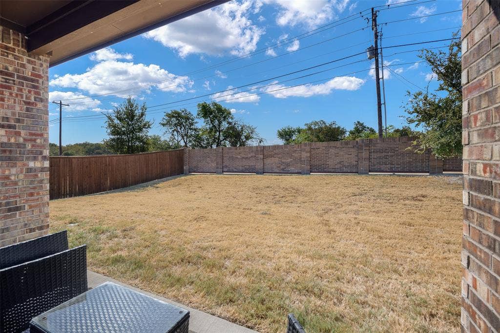 1101 Crepe Myrtle Lane, Anna, TX 75409 Expansive outdoor space featuring a concrete patio, brick exterior wall, and a combination of wood and brick privacy fencing