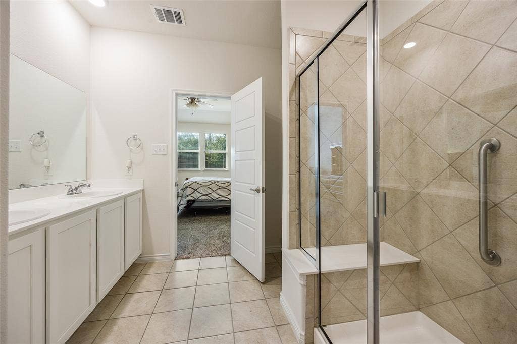 1101 Crepe Myrtle Lane, Anna, TX 75409 Double vanity with undermount sinks, tile flooring, glass-enclosed shower, and a built-in shower bench