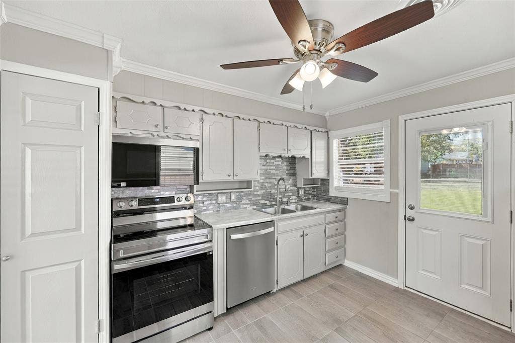 605 NE 33rd Street, Grand Prairie, TX 75050 Kitchen featuring stainless steel appliances, white cabinetry, tile backsplash, wood-finish flooring, and a ceiling fan