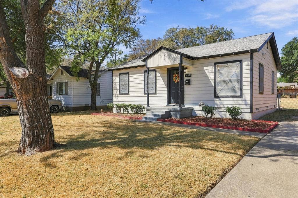 605 NE 33rd Street, Grand Prairie, TX 75050 White siding exterior with dark trim accents, covered front entry, concrete walkway, and mature trees