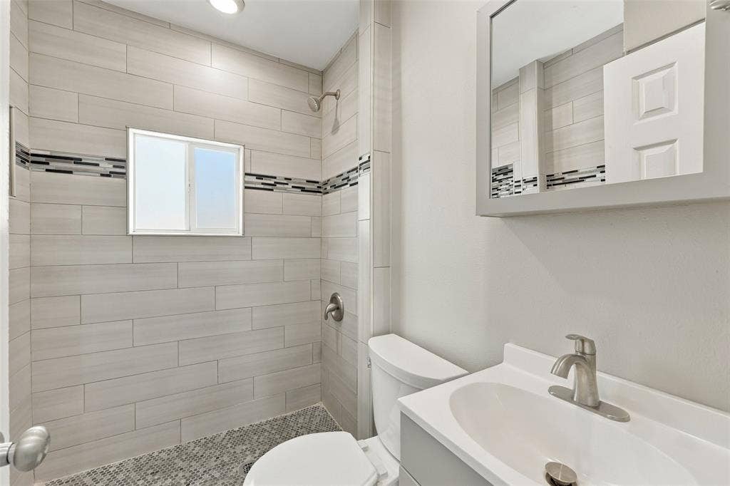 605 NE 33rd Street, Grand Prairie, TX 75050 Shower with light gray rectangular tile, mosaic accent tile, and pebble flooring