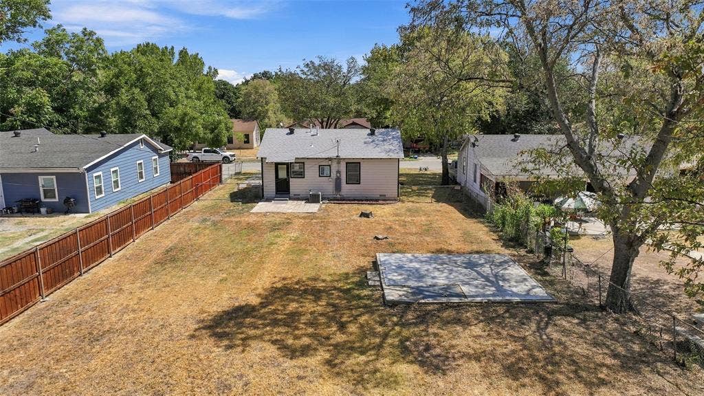 605 NE 33rd Street, Grand Prairie, TX 75050 Expansive backyard featuring a privacy fence, mature trees, and a concrete patio
