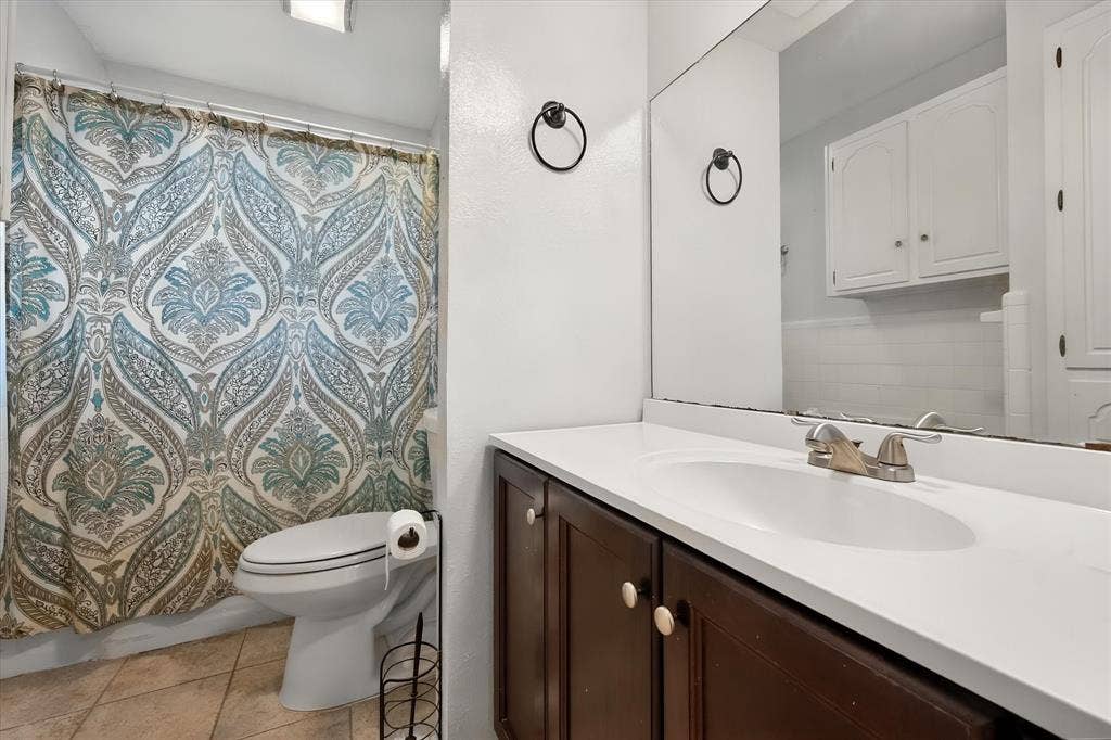 144 Jill Ann Drive, Burleson, TX 76028 Undermount sink with a brushed nickel faucet, large vanity mirror, and white upper cabinetry