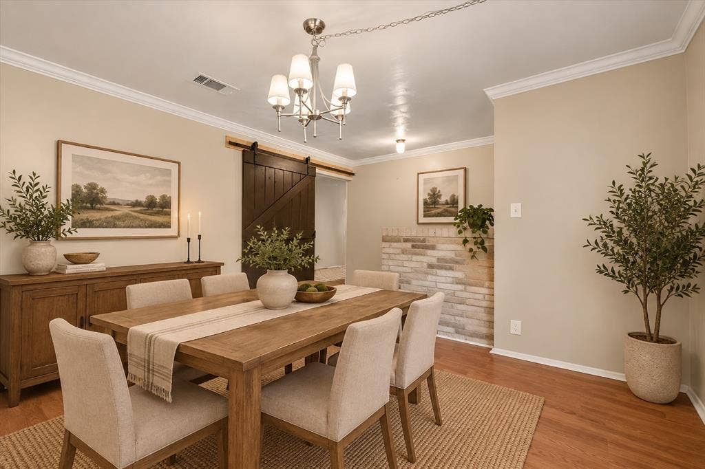 144 Jill Ann Drive, Burleson, TX 76028 Hardwood flooring, crown molding, a dark wood-finish barn door, and a brick-faced accent wall