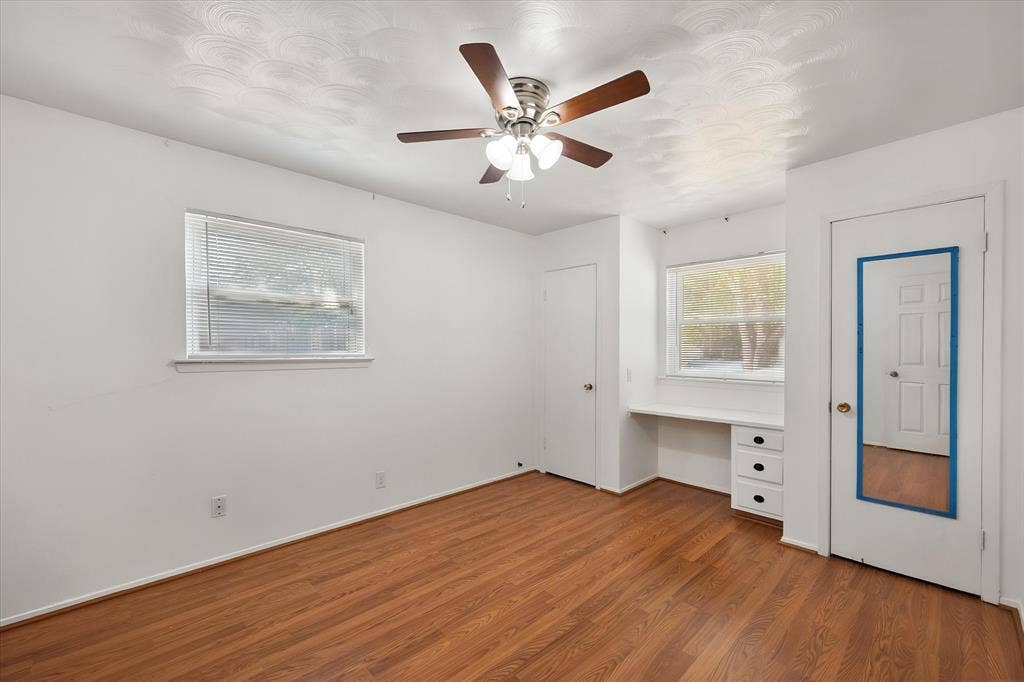 144 Jill Ann Drive, Burleson, TX 76028 Wood-finish flooring, ceiling fan with integrated lighting, built-in desk with drawers, and two windows providing natural light