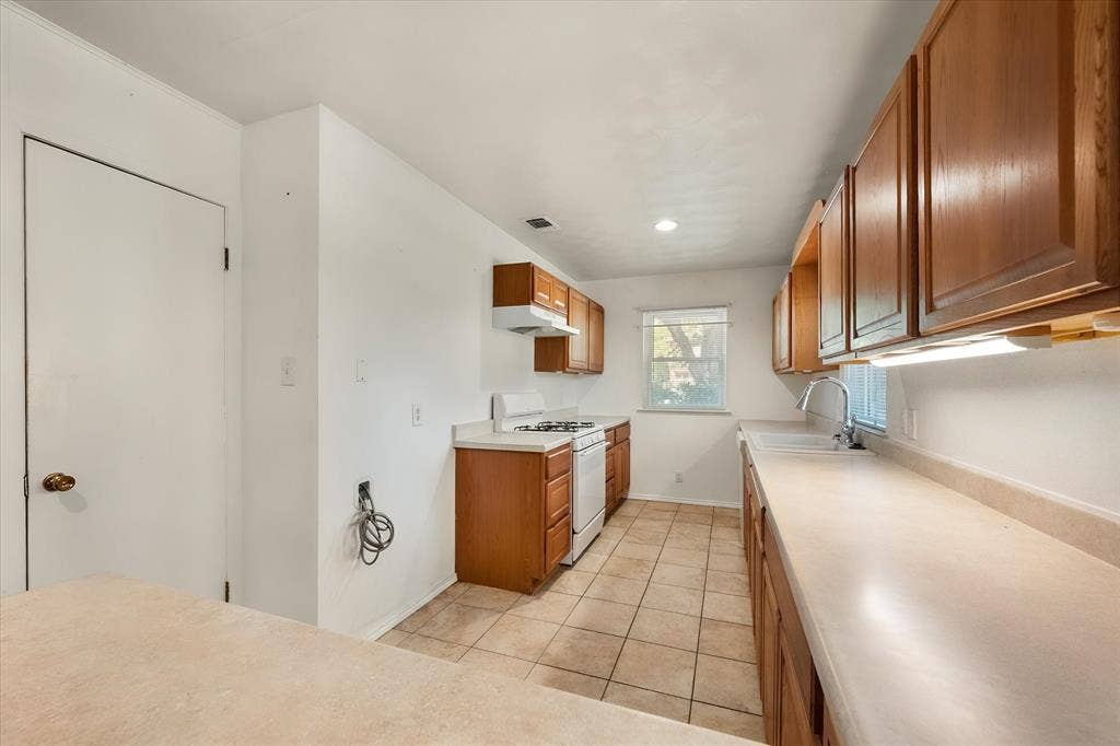 144 Jill Ann Drive, Burleson, TX 76028 Kitchen featuring wood cabinetry, light-toned countertops, white appliances, and tiled flooring