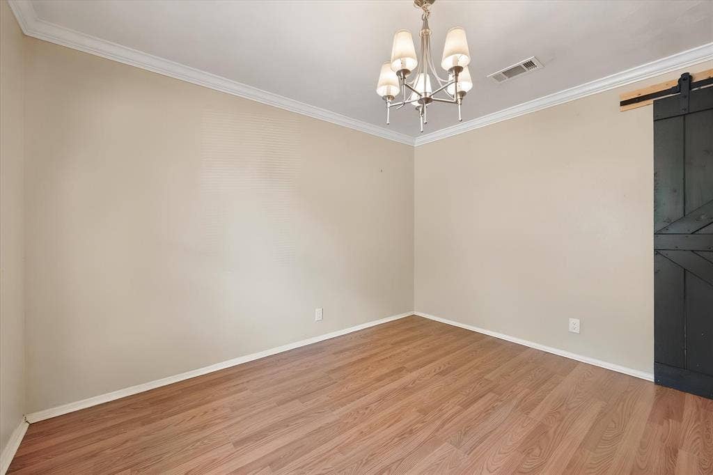 144 Jill Ann Drive, Burleson, TX 76028 Wood-finish flooring, crown molding, and a five-light chandelier complement the neutral wall tones