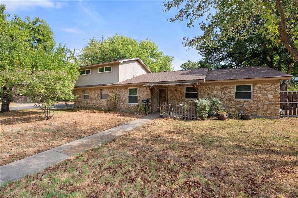 144 Jill Ann Drive, Burleson, TX 76028 Stone veneer exterior with a concrete walkway, mature trees, and a partial picket fence