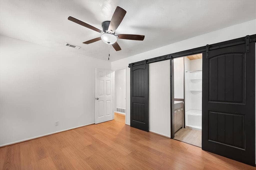 144 Jill Ann Drive, Burleson, TX 76028 Wood-finish flooring, ceiling fan, white paneled door, and black barn doors