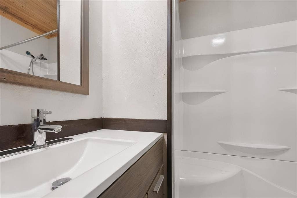 144 Jill Ann Drive, Burleson, TX 76028 White single basin sink with a chrome faucet, set into a dark wood-finish vanity