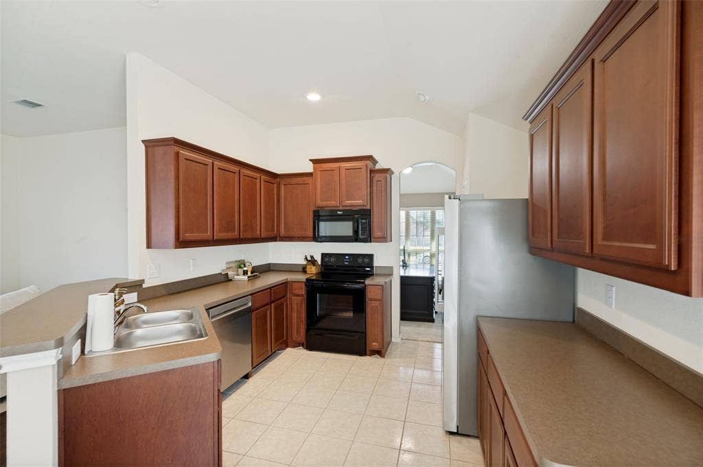 1929 Day Break Drive, Lancaster, TX 75146 Kitchen featuring wood-finish cabinetry, stainless steel double-basin sink, stainless steel dishwasher, and a full suite of appliances