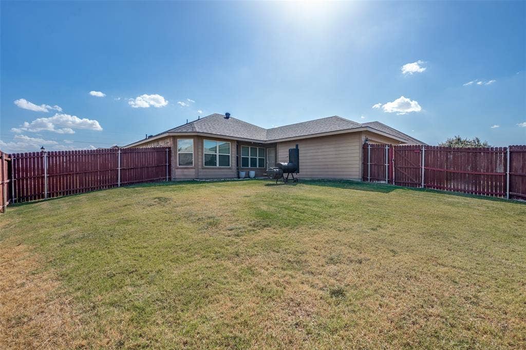 1929 Day Break Drive, Lancaster, TX 75146 Expansive fenced backyard with a manicured lawn and a single-story residence featuring multiple windows and a shingled roof