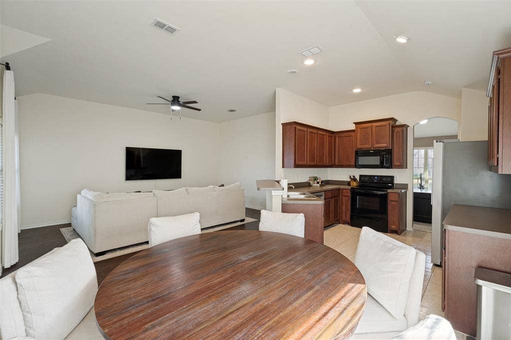 1929 Day Break Drive, Lancaster, TX 75146 Kitchen with wood-finish cabinetry and black appliances, complemented by a breakfast bar
