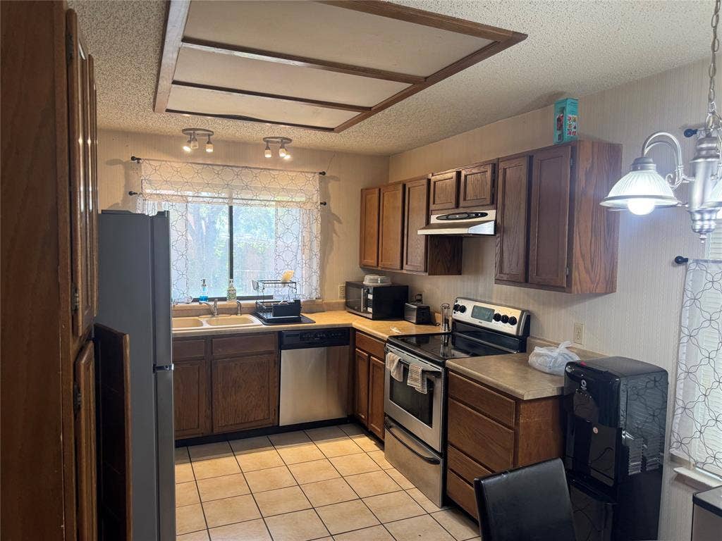 2681 Steppington Street, Grand Prairie, TX 75052 Kitchen featuring wood cabinetry, tiled flooring, stainless steel refrigerator, and ample counter space
