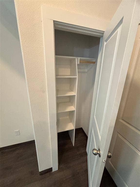 Built-in shelving, hanging rod, wood-finish flooring, white panel door, and brushed nickel door hardware