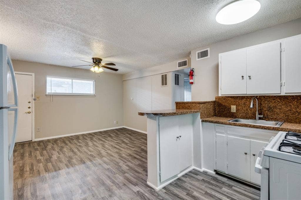 2213 Capri Drive, #208, Fort Worth, TX 76114 Kitchen featuring white cabinetry and a breakfast bar