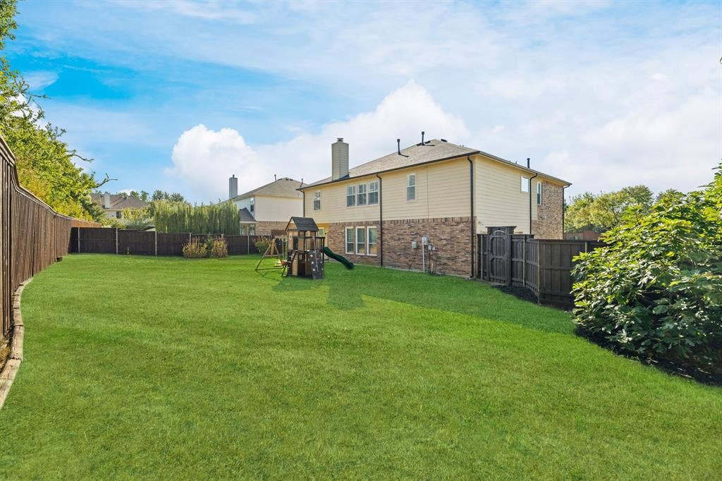 239 Glen Ridge Drive, Murphy, TX 75094 Expansive green lawn with a wooden fence boundary