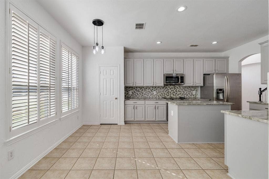 239 Glen Ridge Drive, Murphy, TX 75094 Kitchen featuring white cabinetry, stainless steel appliances, granite countertops, tile flooring, and a decorative tile backsplash