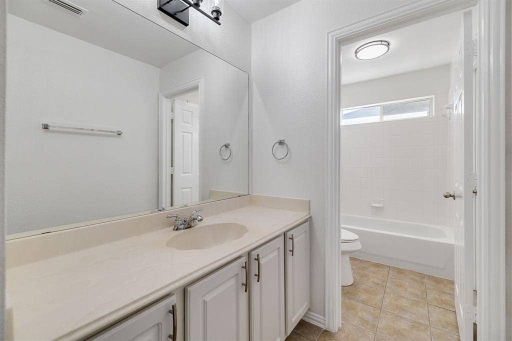 239 Glen Ridge Drive, Murphy, TX 75094 White paneled vanity with chrome hardware, an integrated sink, and an expansive wall mirror