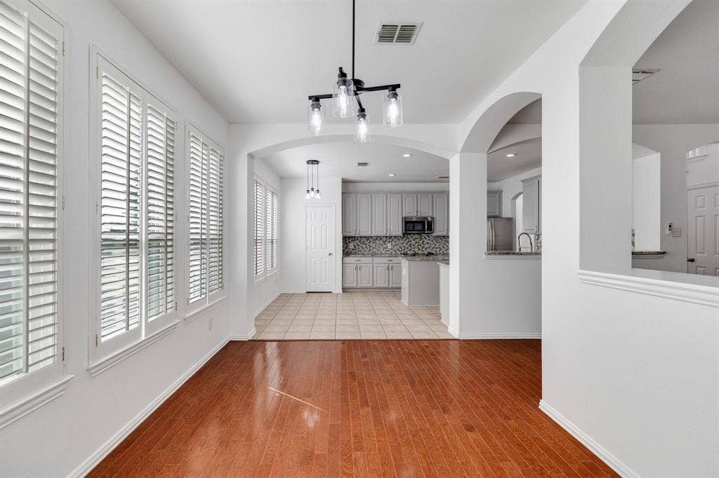 239 Glen Ridge Drive, Murphy, TX 75094 Hardwood-finish flooring, plantation shutters, arched pass-throughs, recessed lighting, and a modern chandelier